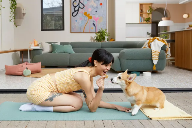Woman feeding supplement to dog on yoga mat
