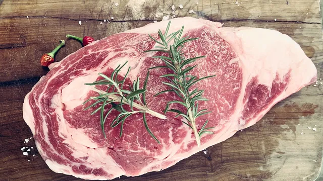raw-cut-of-lamb-on-chopping-board-with-rosemary-twig