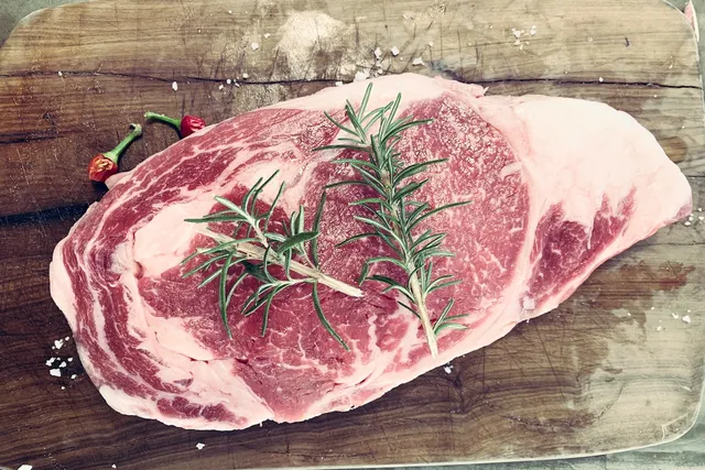 raw-cut-of-lamb-on-chopping-board-with-rosemary-twig