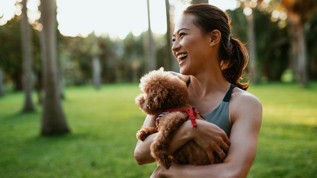 Sporty woman holding fluffy dog in the park