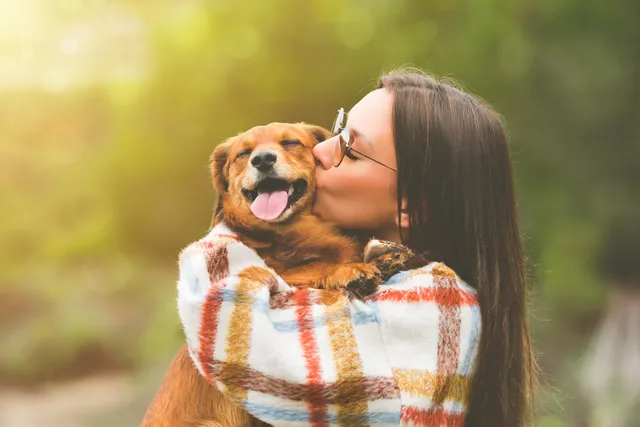 Woman hugging and kissing a happy dog