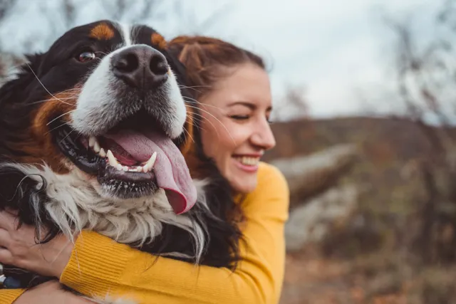 Woman cuddling dog outdoors